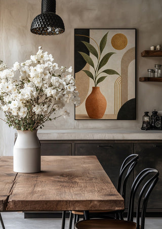 Terracotta Vase with Green Leaves by TimlessArtworks in a black frame above a rustic table with white flowers