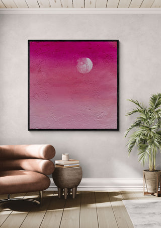 Pink Atmosphere by Marina Agre in a black frame above a pink armchair beside a palm