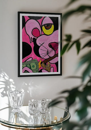 Capitalist Illusion by Bibi in a black frame above a glass table with crystal glassware