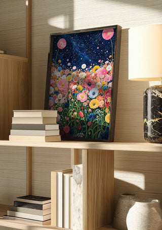 Starlit Flower Field by Yokohama in a dark frame on a wooden shelf beside books and a lamp