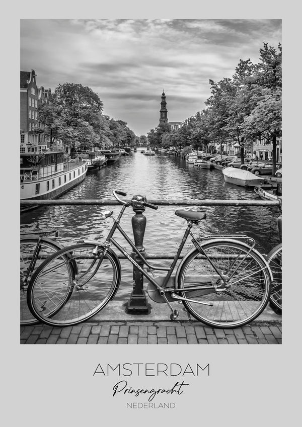 Black and white photo of a bicycle on a bridge over Amsterdam's Prinsengracht canal with boats and trees.