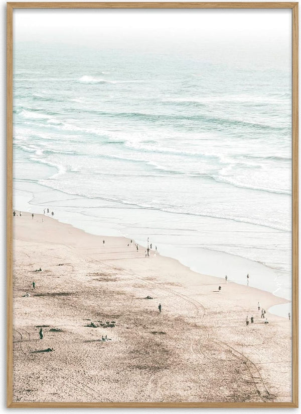 A serene beach scene with gentle waves and people walking along the sandy shore, perfect for coastal decor.