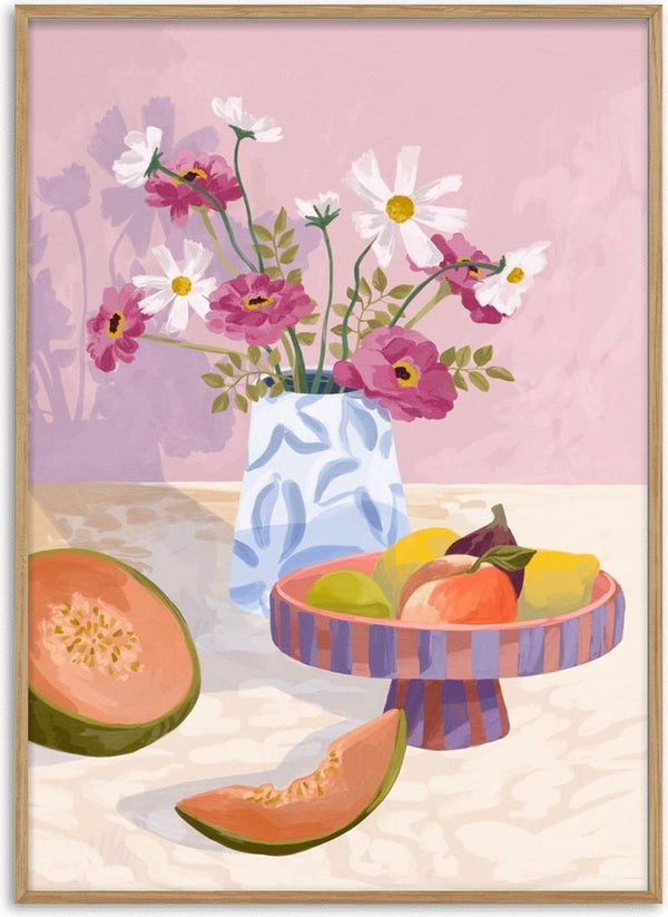 A colorful fruit bowl with guava slices beside a vase of pink and white flowers on a light table.
