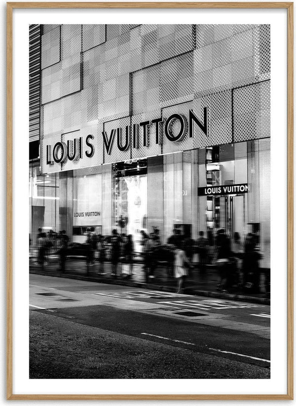 Black and white photo of a Louis Vuitton storefront with people walking outside.